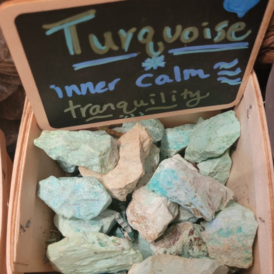 Raw turquoise stones in a wooden box with a sign promoting inner calm and tranquility