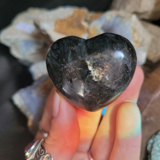 Hand holding a polished heart-shaped Larvakite crystal stone for enhancing psychic abilities and intuition