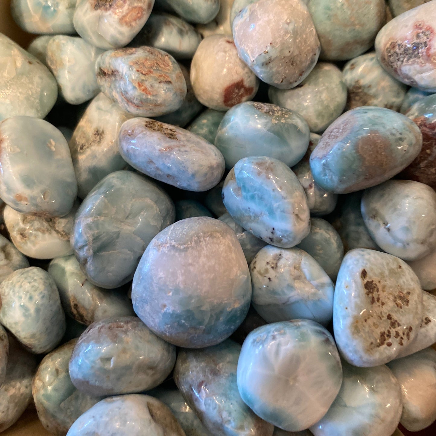collection of polished blue and white Larimar tumble stones with natural brown inclusions