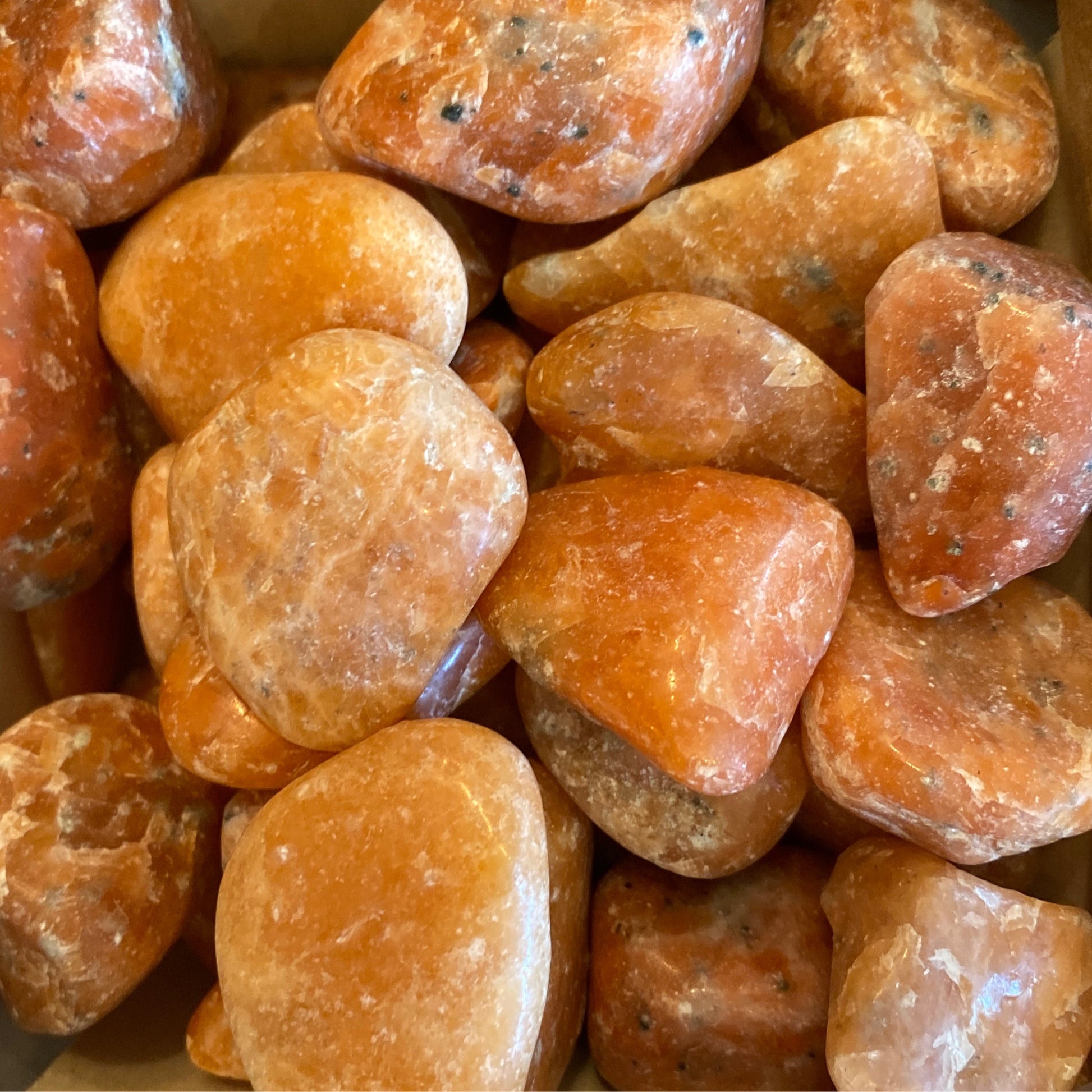 Close-up of polished orange calcite tumble stones promoting creativity and positive energy