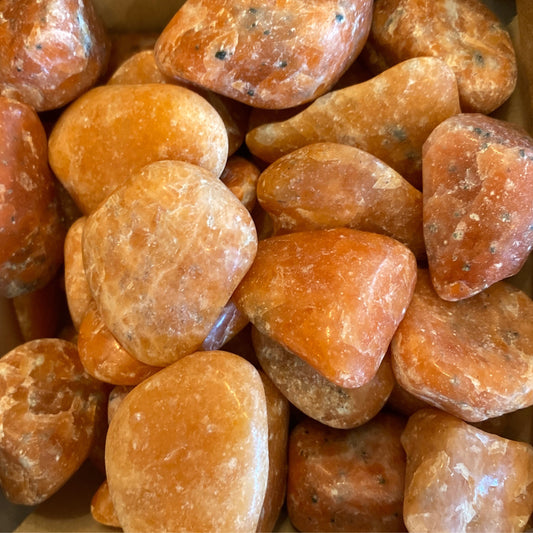 Close-up of polished orange calcite tumble stones promoting creativity and positive energy