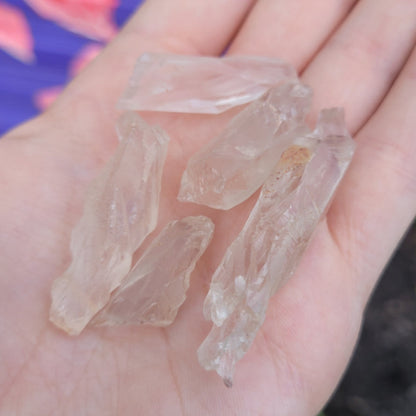 Hand holding raw twisted lemurian quartz crystals with natural smokey appearance