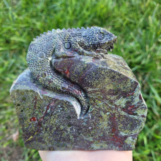 Chameleon Kababa Jasper stone carving of a lizard on green grass background