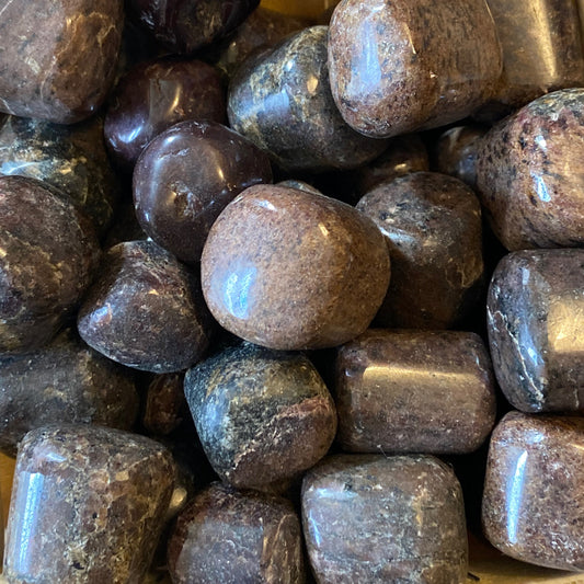 close-up of polished garnet tumble stones with smooth surfaces and deep reddish-brown color