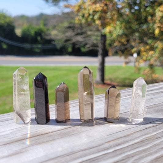 Set of natural Smokey Quartz Obelisk 1-2'' towers on outdoor wooden surface promoting healing and grounding energy