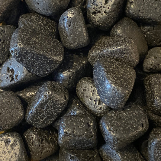 Close-up of natural black lava stone tumbles with porous texture for exfoliating and skin care.