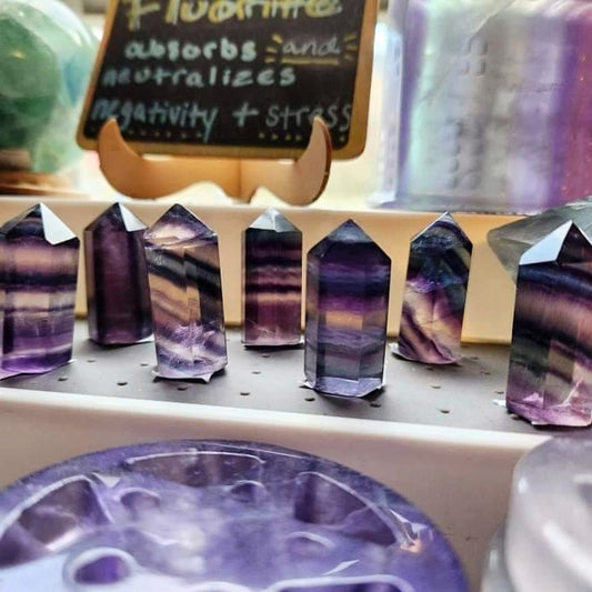 1-2 Inch Fluorite Point crystals in purple and green hues displayed on a shelf for healing and protection