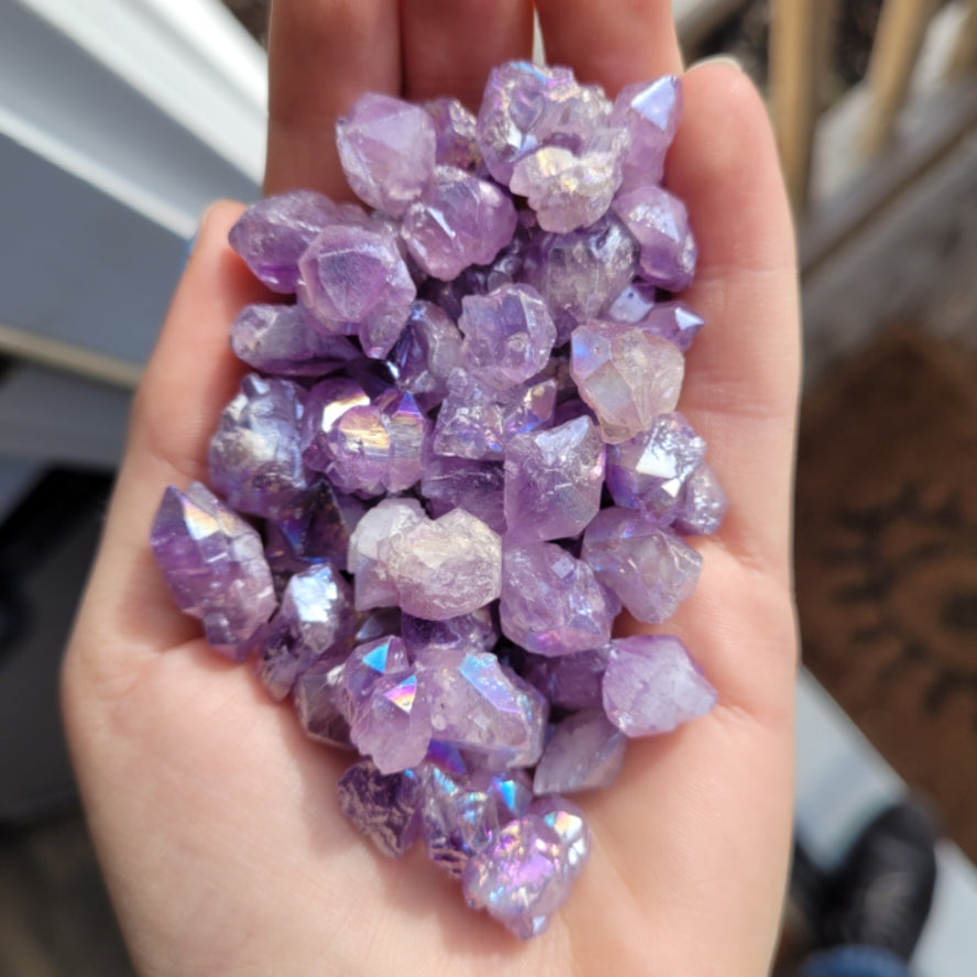 Hand holding raw amethyst flower aura quartz crystals with shimmering purple hues