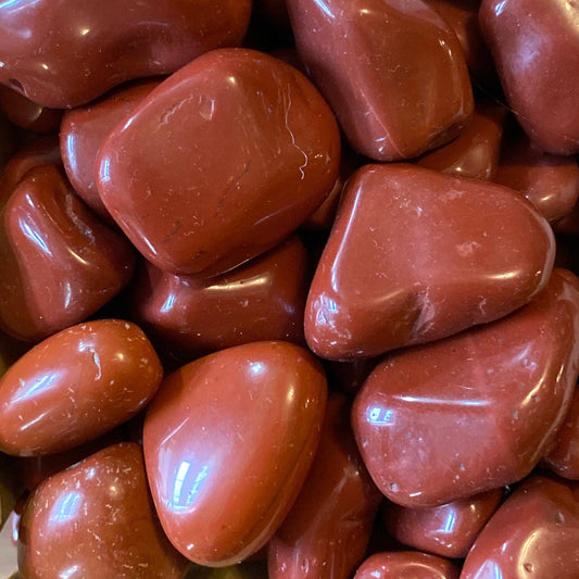 Close-up of polished natural red jasper tumble stones with smooth, glossy surfaces and rich earthy tones