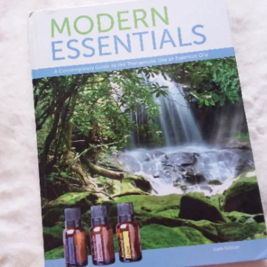 Modern Essentials book with a nature waterfall background and essential oil bottles on the cover