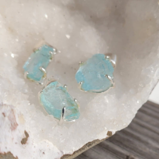 Raw aquamarine pendants with sterling silver fastenings on a white crystal background