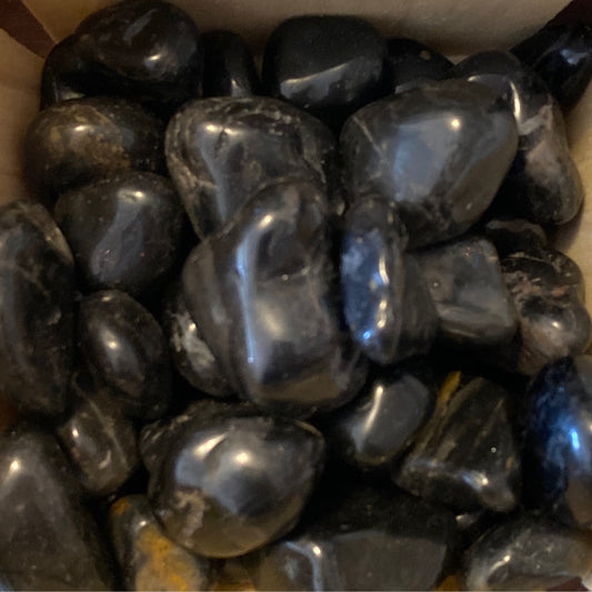 Close-up of polished black onyx tumble stones with smooth shiny surfaces