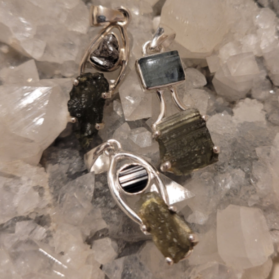 Handcrafted sterling silver Moldavite pendant with crystal amplifier on a bed of clear quartz crystals