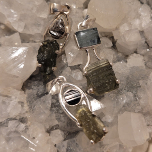 Handcrafted sterling silver Moldavite pendant with crystal amplifier on a bed of clear quartz crystals