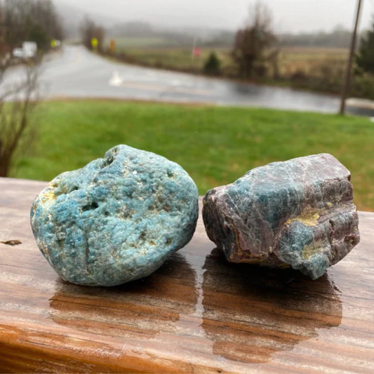 Raw Blue Apatite stones on wooden surface with blurred outdoor background