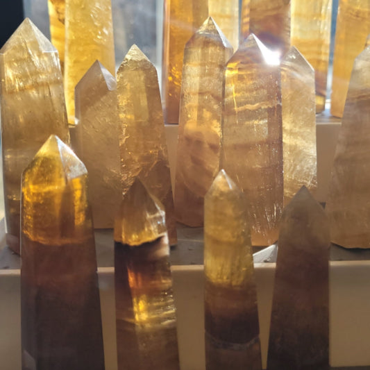 Collection of polished yellow fluorite towers with pointed tips displayed closely together