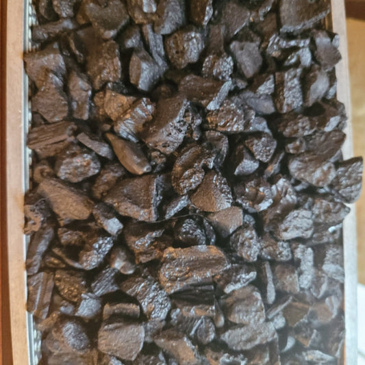 Raw black Tektite stones with natural rough texture, formed from meteorite impact, used for spiritual energy work and grounding.