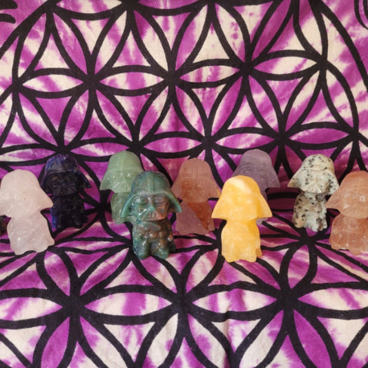 Crystal Darth Vader figurines in a variety of colorful stones displayed on a purple and black patterned cloth
