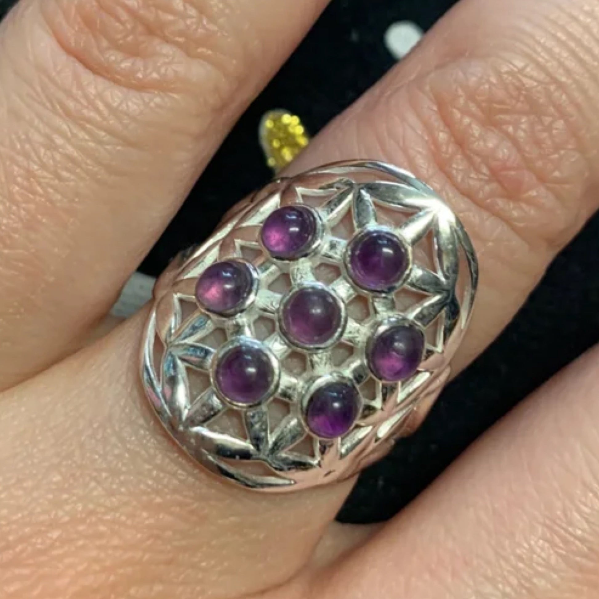 Adjustable sterling silver ring with amethyst stones arranged in a Flower of Life pattern on finger