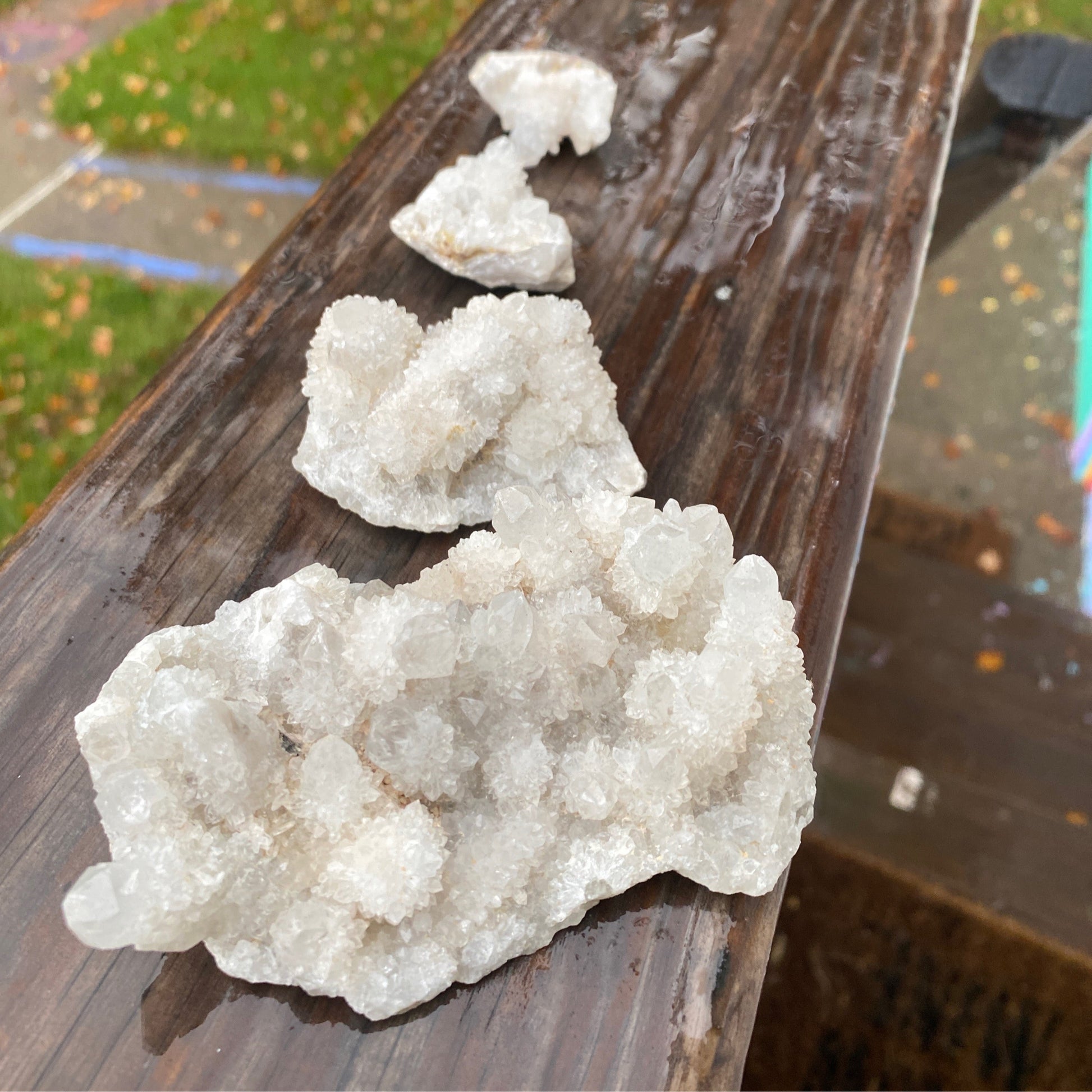 White Spirit Quartz crystal cluster with sparkling formations on wooden surface outdoors