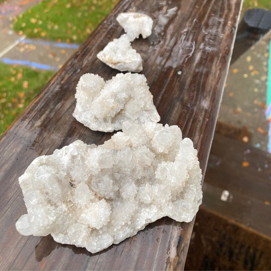White Spirit Quartz crystal cluster with sparkling formations on wooden surface outdoors