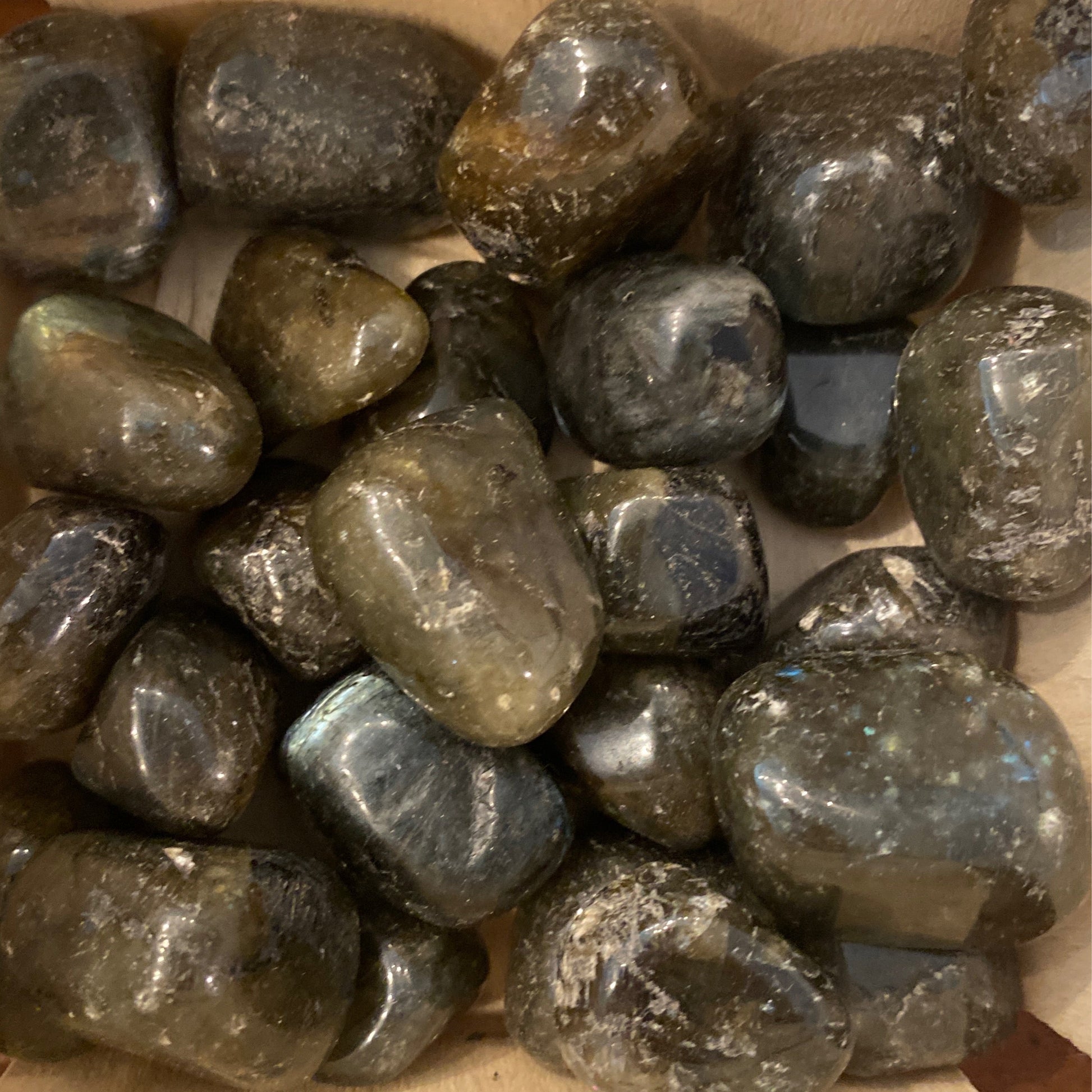 Pile of polished tumble labradorite stones showcasing iridescent flashes and smooth surfaces