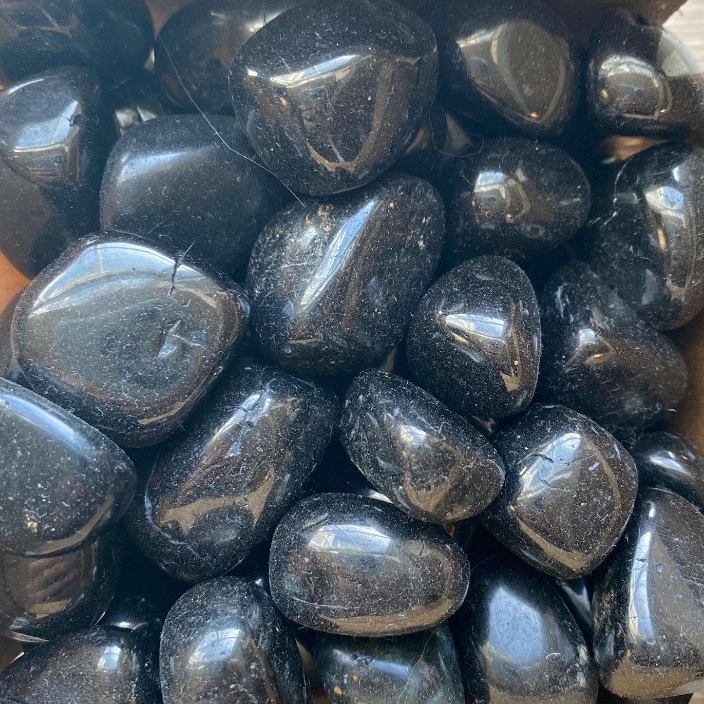 close-up of polished black jet tumble stones with smooth shiny surfaces