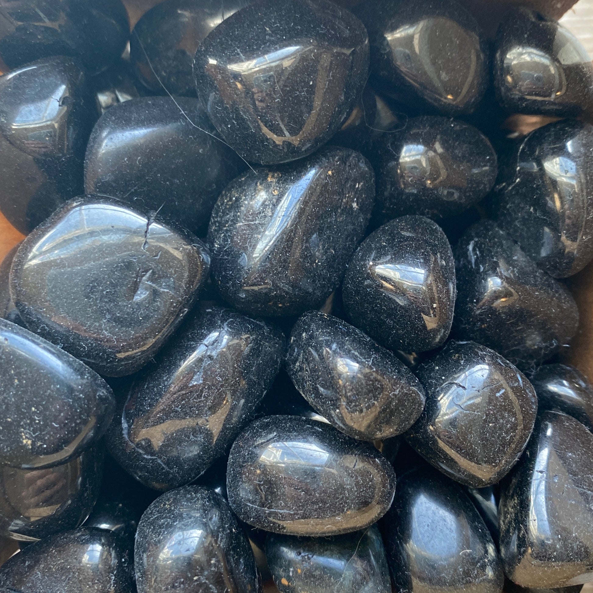 close-up of polished black jet tumble stones with smooth shiny surfaces