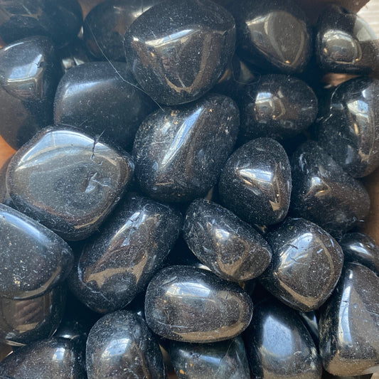 close-up of polished black jet tumble stones with smooth shiny surfaces