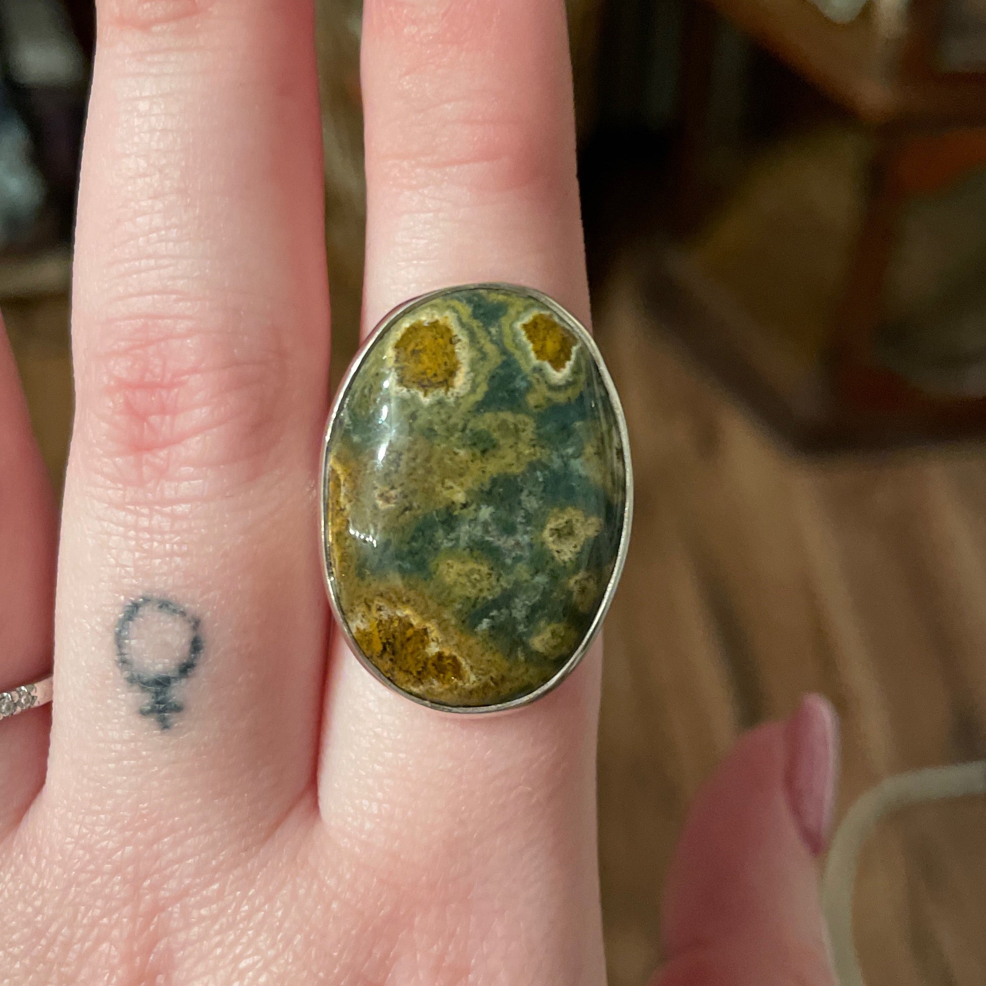 Adjustable ring with oval ocean jasper stone on finger