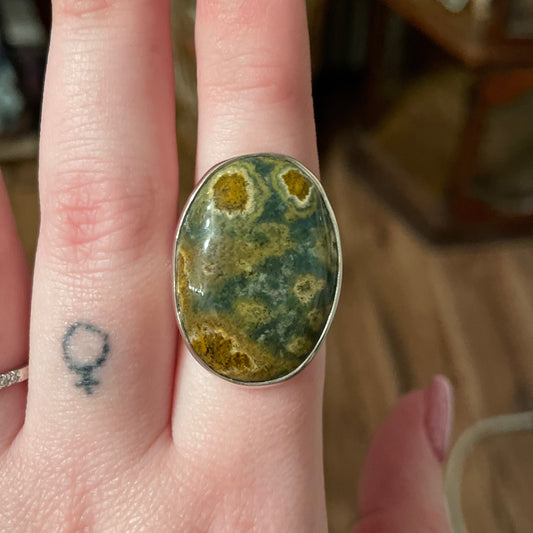 Adjustable ring with oval ocean jasper stone on finger