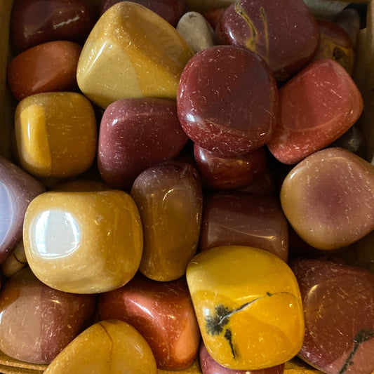 Polished tumble Mookaite stones in various earthy shades of red, yellow, and brown for grounding and balance.