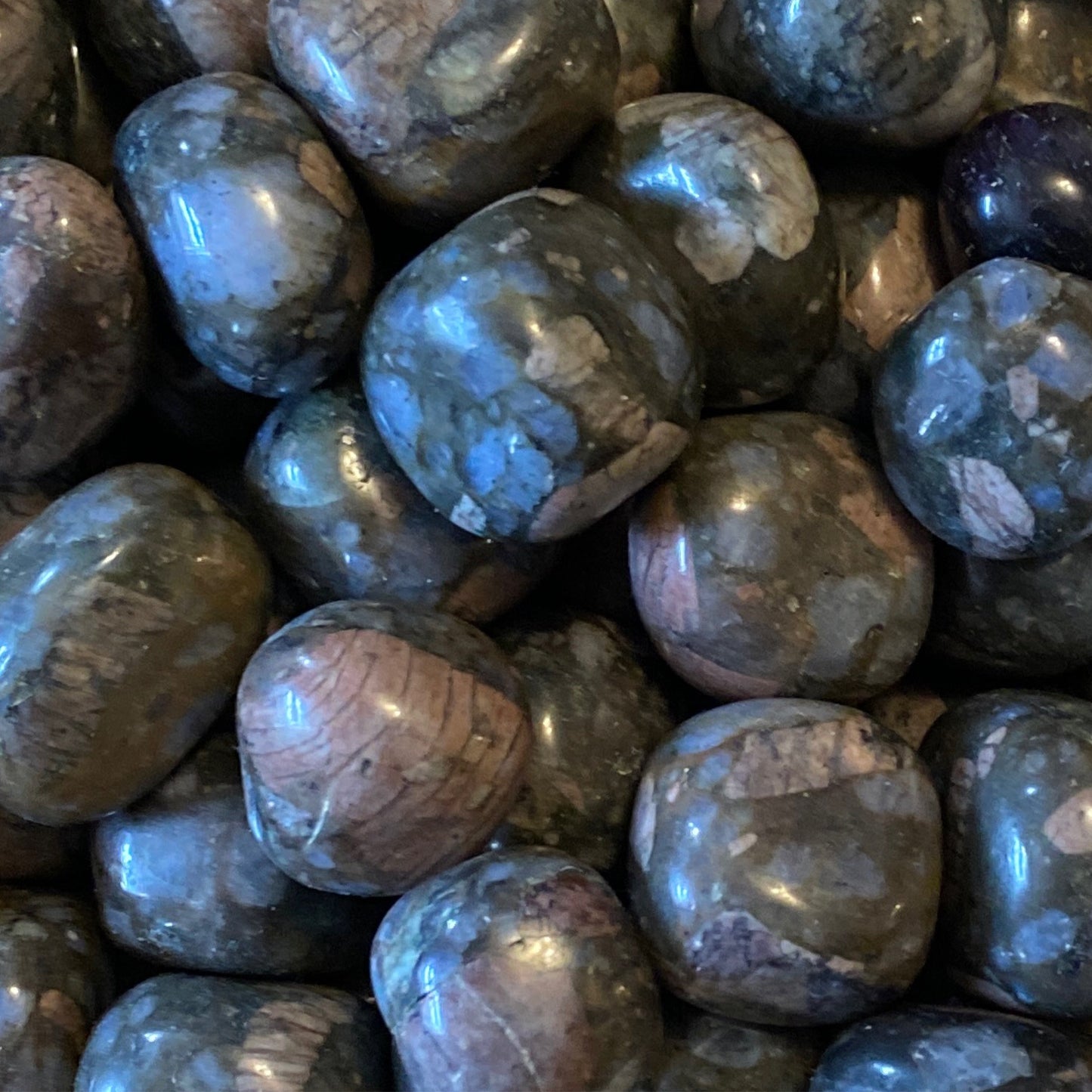 Close-up of smooth, polished Sera Tumble crystals with gray and pink hues promoting chakra balance and inner harmony
