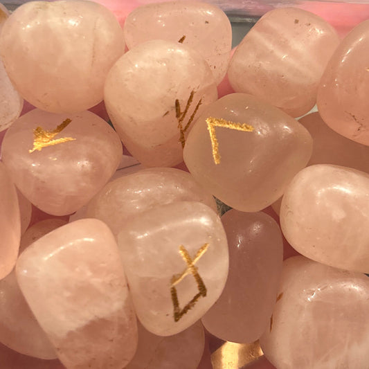 Rose quartz gemstone rune set with gold engraved symbols for divination and spiritual practice