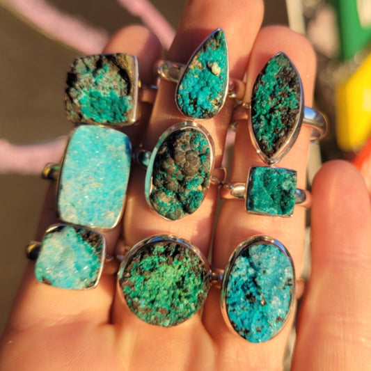 Handcrafted rings featuring unique dioptase, chrysocolla, and druzy stones in various shapes and vibrant blue-green hues