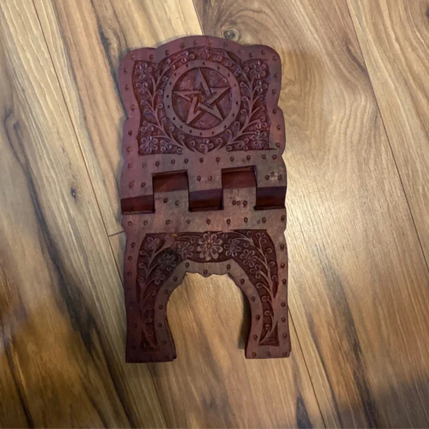 Wooden Pentacle Book Stand with intricate carved floral and star designs on a polished surface.