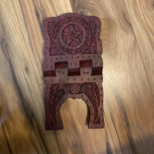 Wooden Pentacle Book Stand with intricate carved floral and star designs on a polished surface.