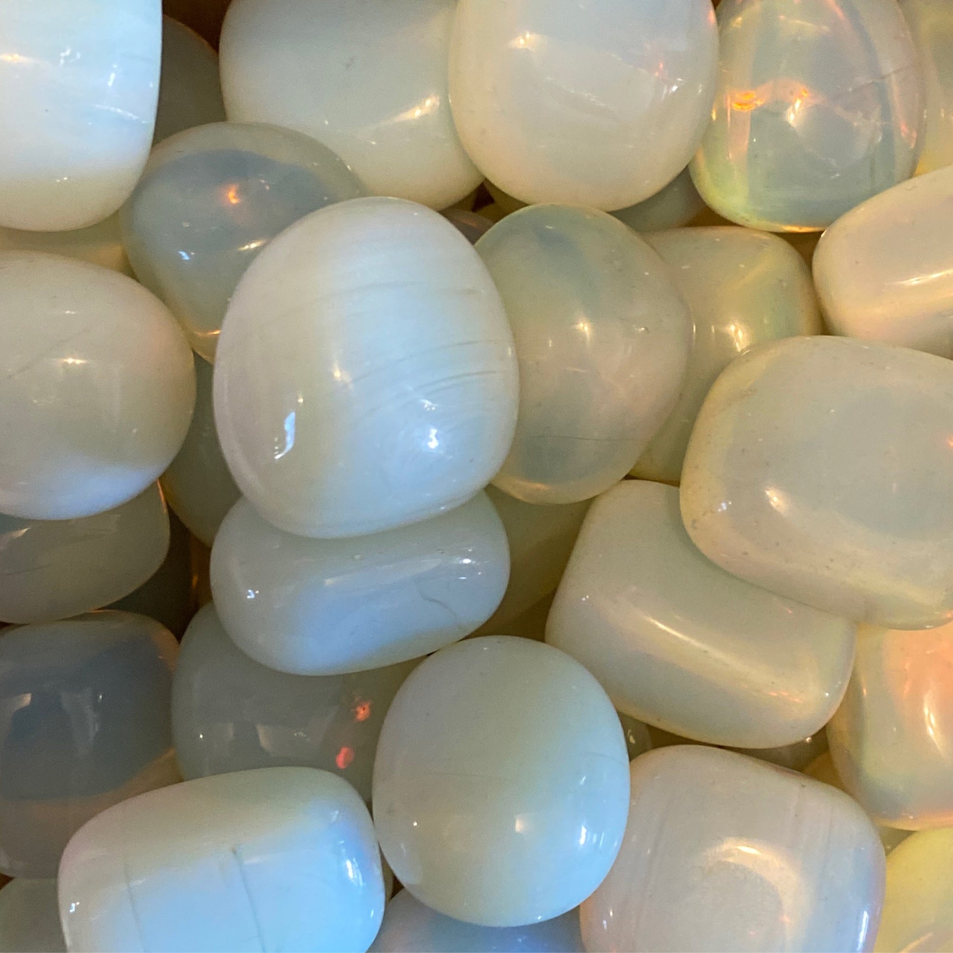 Close-up of smooth, polished opalite tumbles glowing with soft iridescent light