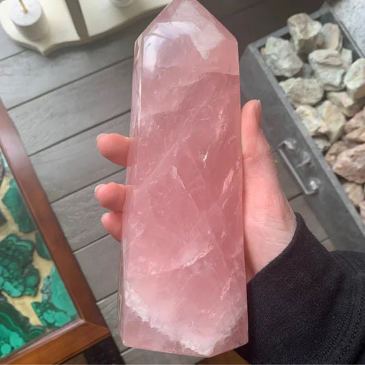 Hand holding a polished pink rose quartz tower crystal with natural white inclusions