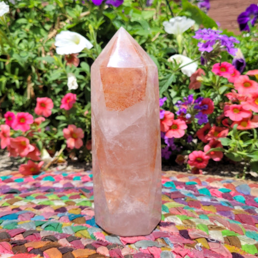 Fire Quartz Towers standing upright on colorful woven mat with vibrant flowers in the background