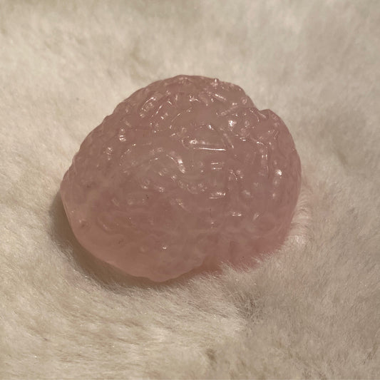 Mini anatomical rose quartz brain sculpture 1-2 inches on soft fabric background