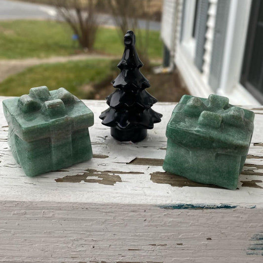 Green aventurine gift boxes with a black decorative tree on a wooden surface outdoors