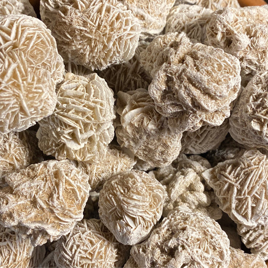 Close-up of multiple beige Desert Rose tumble stones with intricate crystal patterns