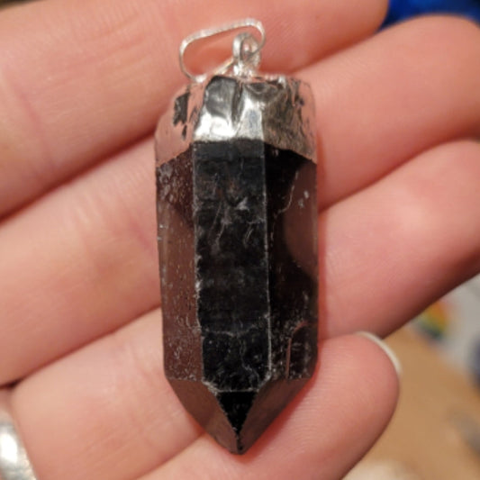 Smokey quartz raw point pendant held in hand with silver cap and loop