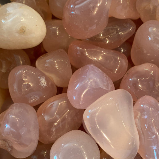 Close-up of polished natural pink chalcedony tumble stones with smooth surfaces and soft pink hues