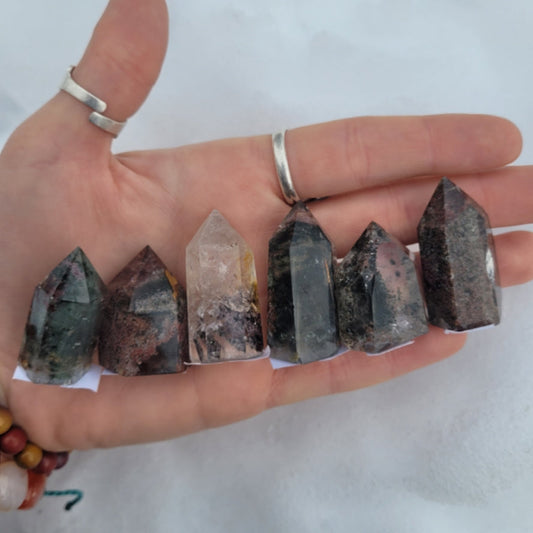Hand holding six polished Garden Lodolite Point crystals with varying colors and clarity